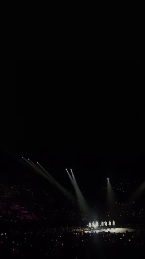 Bts Performing On Stage In Front Of Their Enthusiastic Fans Wallpaper