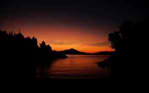 Calm Waters With Trees And Mountains During Evening Wallpaper