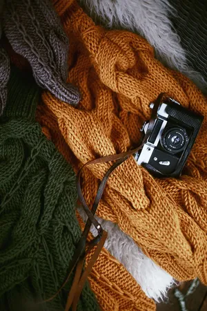 Camera On Top Of A Bronze Colored Knit Sweater Wallpaper