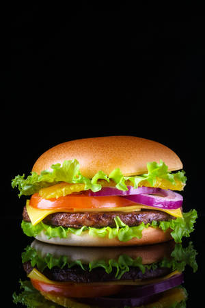 Caption: A Delectable Cheeseburger On A Dark Backdrop Wallpaper