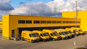 Caption: A Dhl Delivery Van In A Parking Area Wallpaper