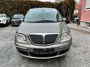 Caption: A Silver Lancia Phedra Parked Outdoors Wallpaper