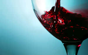 Caption: Elegant Red Wine Glass In Mood Lighting Wallpaper