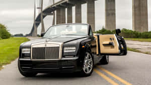 Caption: Luxurious Rolls Royce Phantom Drophead Coupe Against An Epic Sunset Wallpaper