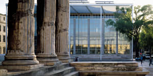 Caption: Maison Carrée Juxtaposed With Modern Architecture Wallpaper