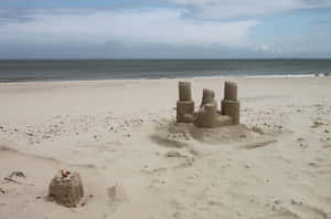 Caption: Majestic Sandcastle By The Seashore Wallpaper