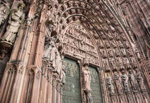 Caption: Majestic Strasbourg Cathedral Against A Clear Blue Sky Wallpaper