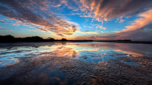 Caption: Majestic Sunset Reflection On Calm Waters Wallpaper