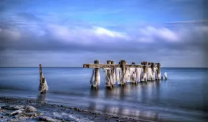 Caption: Majestic Winter Beach – Where Snow Meets The Sand Wallpaper