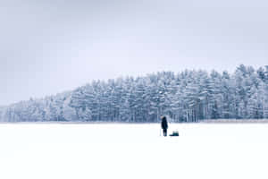 Caption: Man Fishing On A Frozen Lake Wallpaper