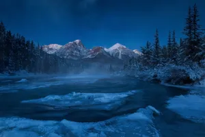 Caption: Pristine Rocky Mountains Under The Starlit Sky Wallpaper