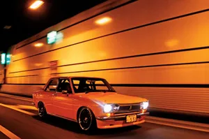 Caption: Sleek Red Datsun Showcased Outdoors Wallpaper