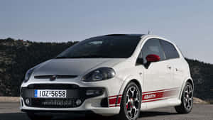 Caption: Sleek Red Fiat Punto Cruising On The Road Wallpaper