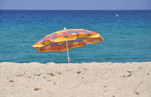 Caption: Vibrant Beach Umbrella On A Sunny Day Wallpaper