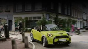 Caption: Vibrant Mini Cooper Convertible Cruising On A Sunny Day Wallpaper