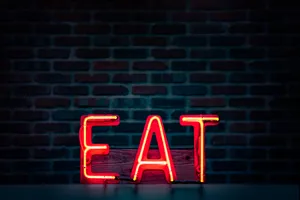 Caption: Vibrant Neon Sign Encouraging To 'eat' Wallpaper