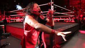 Caption: Wwe Star Shinsuke Nakamura Displaying Rock Horns In Red Vest Wallpaper