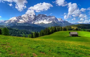 Captivating Spring Mountain Landscape With Lush Greenery And Blue Sky Wallpaper