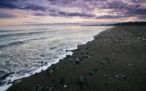 Catch The Sun Setting On The Serene Black Sand Beach Wallpaper