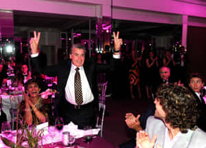 Charismatic Manuel Santana Displaying A Peace Sign At A Vibrant Party. Wallpaper