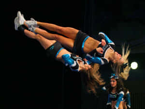 Cheerleaders In Mid Air Stunt Wallpaper
