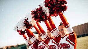 Cheerleading Squad Raising Pom Poms Wallpaper