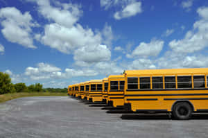 Children Boarding A Yellow School Bus On A Sunny Day Wallpaper