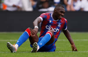 Christian Benteke Sitting On Football Field Wallpaper