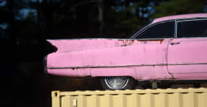 Classic Pink Cadillac Parked In A Picturesque Setting Wallpaper