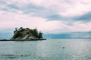 Coastal_ Islet_ Under_ Cloudy_ Skies Wallpaper