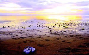 Colorful Beach Sandals On Sandy Shore Wallpaper