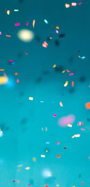 Colorful Confetti Falling Against Blue Background Wallpaper