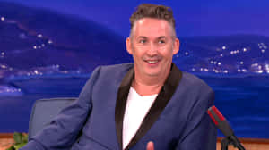 Comedianin Blue Blazer Talk Show Appearance Wallpaper