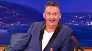 Comedianin Blue Blazer Talk Show Appearance Wallpaper