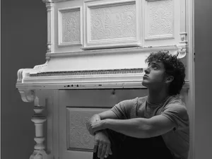Contemplative Man Beside Piano Wallpaper