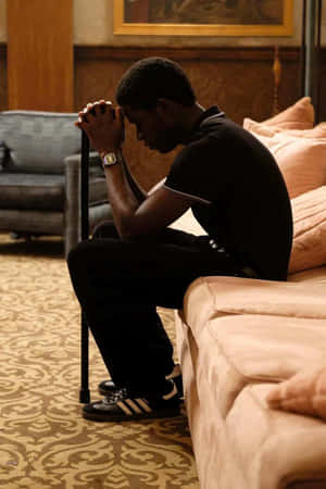 Contemplative Man Seatedon Couch Wallpaper