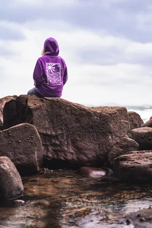 Contemplative Personin Purple Hoodieon Rocks Wallpaper