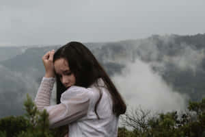 Contemplative Young Girl Misty Mountain Backdrop Wallpaper