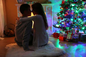 Couple Embracing Christmas Tree Backdrop Wallpaper