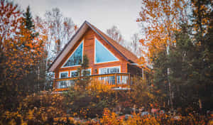 Cozy Fall Cabin Surrounded By Autumn Foliage Wallpaper