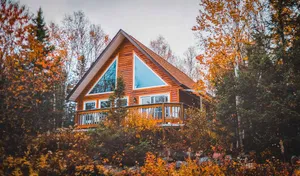 Cozy Fall Cabin Surrounded By Autumn Foliage Wallpaper