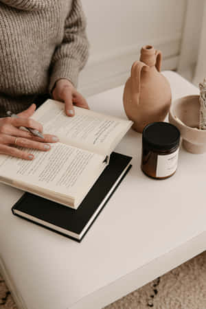 Cozy Reading Momentwith Ceramicsand Candle Wallpaper