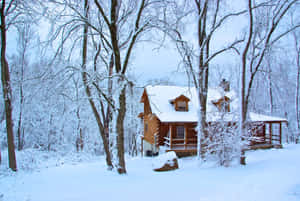 Cozy Winter Cabin Nestled In Snowy Forest Wallpaper