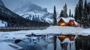 Cozy Winter Cabin Nestled In Snowy Forest Wallpaper