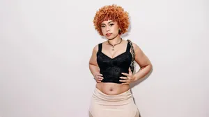 Curly Haired Woman In Black Top And Beige Skirt Wallpaper