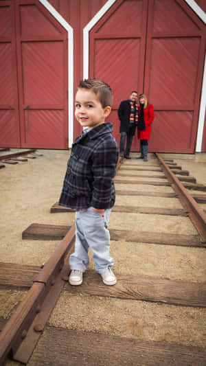 Cute Boy Smiling Near Red Barn Doors Wallpaper