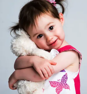 Cute Photo Of A Young Girl Hugging Her Tangible White Stuffed Toy Wallpaper