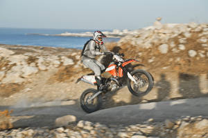 Daredevil Dirtbike Rider Showcasing Wheelie Uphill Wallpaper