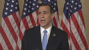 Darrell Issa Standing Proudly In Front Of Four American Flags Wallpaper