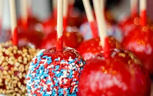 Delectable Candy Apples On Wooden Table Wallpaper